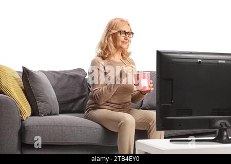 Frau vor dem fernseher, die Nudeln aus einer Take-away-Box auf weißem Hintergrund isst Stockfoto