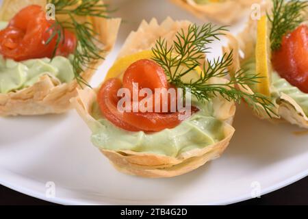 Avocado mit Frischkäse in das zarteste Mousse, eine Scheibe Lachs und Zitrone geschlagen. Serviert in knusprigen Körben mit eingebackenem Phyllo-Teig Stockfoto