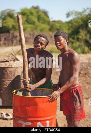 Andranovory, Madagaskar - 30. April 2019: Zwei unbekannte madagassische Männer, die Saft aus Früchten in einem großen Fass mit Holzstange extrahieren - dies ist zu verwenden Stockfoto