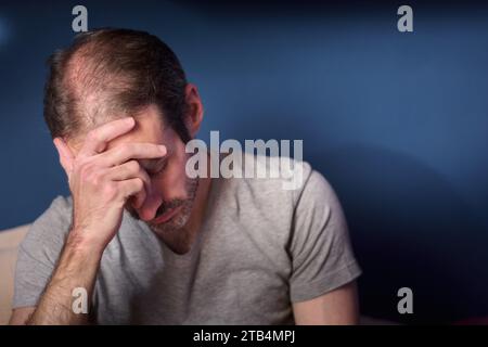 Junger 30-jähriger kaukasier mit kurzem Bart, der den Kopf hält. Vorstellung von Depression, Verlust und Trauer. Erwachsene Person, die Stress und Angst ausdrückt. Stockfoto
