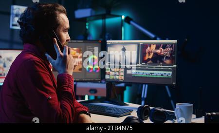 Videoredakteur empfängt Telefonanrufe und ordnet aufgezeichnete Clips in einem kreativen Medienstudio nahtlos zusammen. Videofilmer, der mit dem Regisseur auf dem Smartphone spricht, während er aufgenommene Aufnahmen zusammenstellt Stockfoto