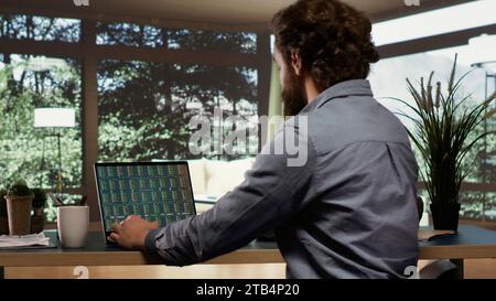 Selbständiger Banker, der Trends an der Börse von seiner extravaganten Luxuskabine im Wald aus verfolgt und den Laptop öffnet, um Anlageaktualisierungen zu sehen. Unternehmer, der in einer reichen Bergvilla lebt. Stockfoto