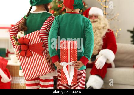 Kleine Elfen verstecken Weihnachtsgeschenke vor dem Weihnachtsmann zu Hause, Rückansicht Stockfoto