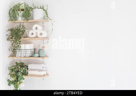 Schönes weißes Badezimmer. Holzregale. Gerollte Handtücher, gestapelte Handtücher und Körbe. Stockfoto