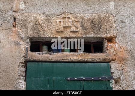 Über der Tür mit dem religiösen Symbol „IHS“, einem Christogramm, das die ersten drei Buchstaben des griechischen Namens Jesu, Finale Ligure, Savona, kennzeichnet Stockfoto