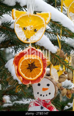 Runde Scheibe Orangen, Fuchs, Schneemann Winterschnee Weihnachtsdekoration hängt draußen am Weihnachtsbaum im Winter Stockfoto