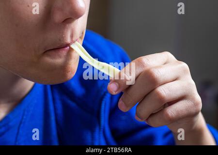 Junge isst hausgemachte Nudeln mit langen Händen und saugt sich die Lippen in den Mund Stockfoto