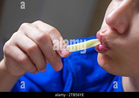 Junge isst hausgemachte Nudeln mit langen Händen und saugt sich die Lippen in den Mund Stockfoto