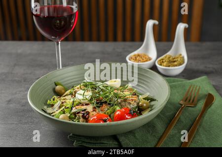 Leckeres Gericht mit Estragon, Salatdressings und einem Glas Wein auf grauem Tisch Stockfoto