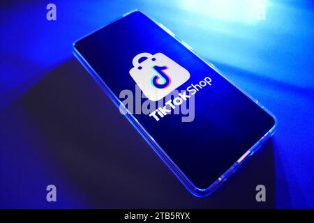 Ein Smartphone mit TikTok Shop Logo auf dem Bildschirm mit blauem Hintergrund. Ähnliches Bild in meinem Portfolio. Stockfoto