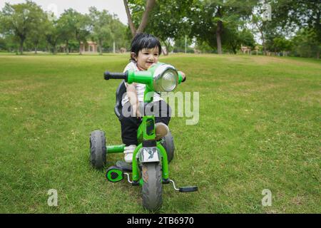 Niedliches kleines Kleinkind fährt das Dreirad. Kleinkind mit dem Fahrrad im Park oder Garten. Fahrradfahren lernen. Stockfoto