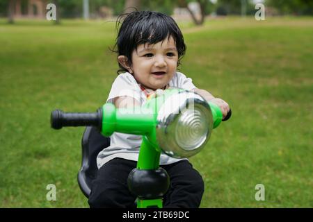Niedliches kleines Kleinkind fährt das Dreirad. Kleinkind mit dem Fahrrad im Park oder Garten. Fahrradfahren lernen. Stockfoto