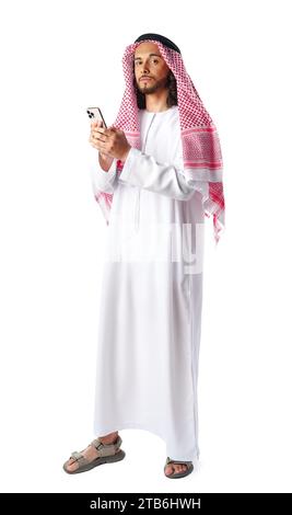 Junger arabischer Mann in traditioneller Kleidung, der ein Smartphone auf weißem Hintergrund benutzt Stockfoto