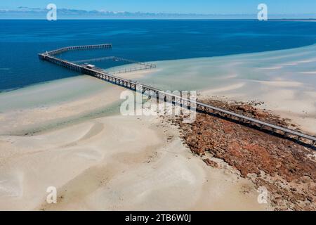 Aus der Vogelperspektive auf einen langen schmalen Steg, der über Felsen und Strand zum tieferen Wasser in der Moonta Bay auf der Yorke Peninsula in Südaustralien führt Stockfoto