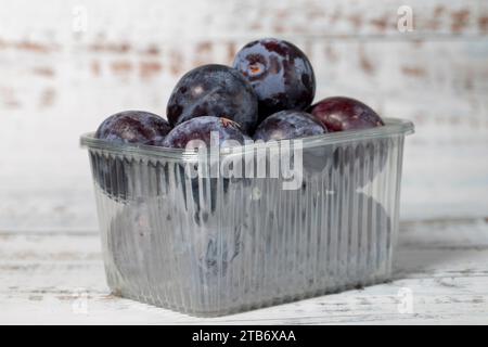 Frische schwarze Pflaumen auf weißem hölzernem Hintergrund. Ökologische Agrarerzeugnisse. Köstliche schwarze Pflaumen Stockfoto