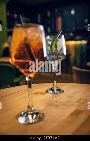 Aperol Spritz- und Gin Tonic-Cocktails in Weingläsern auf dem Bartisch Stockfoto