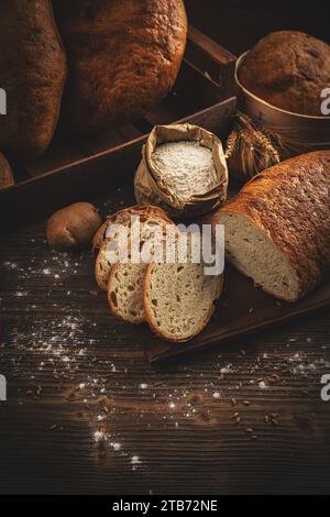 Handwerklich geschnittene Brotlaibe auf dunklem Holzhintergrund Stockfoto