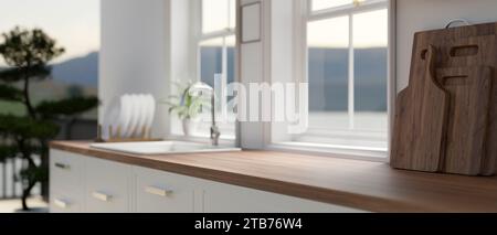 Seitenansicht eines Raumes auf einer hölzernen Küchenarbeitsfläche mit Holzschneidebrettern, einem Waschbecken am Fenster und einer Zimmerpflanze in einem modernen, minimalen Stil Stockfoto