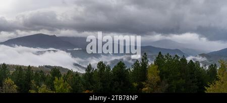 Ein Panoramablick mit Bergen und grünem Wald unter einem bewölkten Himmel mit Nebel in den Tälern Stockfoto