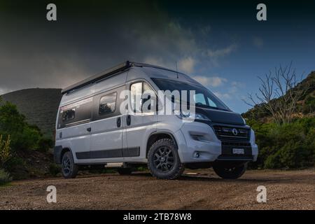 Ein flacher Blick auf einen grauen Wohnmobil, der auf einer roten Feldstraße parkt Stockfoto