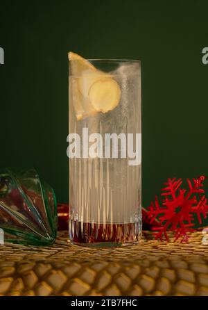 Gin Tonic in Glas mit hoher Kugel mit Zitrone und Eis mit Glaskugeln vor grünem Hintergrund Stockfoto