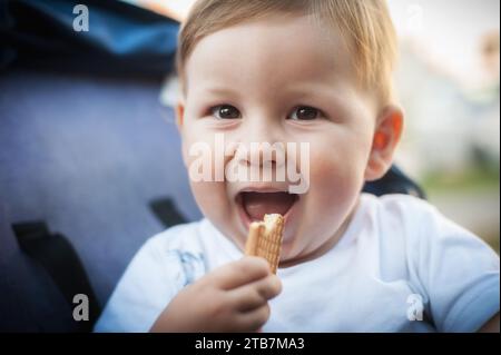 Porträt des glücklichen und lächelnden süßen Jungen, der sein Lieblingskeks isst. Gesunde Ernährung für Kinder Konzept Stockfoto