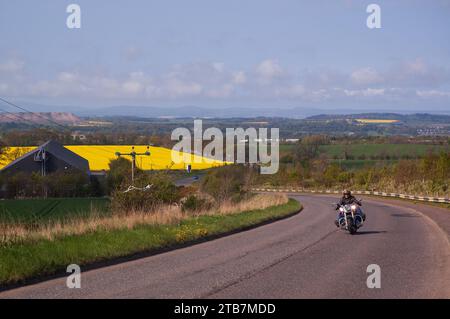 Alleinmotorradfahrer, der durch die Landschaft mit blauem Himmel fährt. Stockfoto