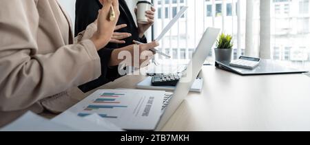 Das Business Team und zwei Kollegen diskutieren die Daten aus dem Finanzdiagramm und dokumentieren den Laptop, um Verhandlungen zu kontaktieren. Planung am Schreibtisch Stockfoto