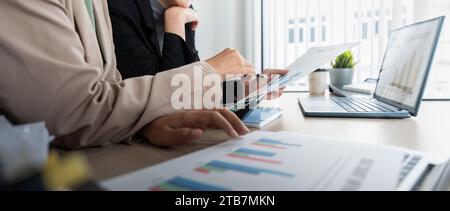 Das Business Team und zwei Kollegen diskutieren die Daten aus dem Finanzdiagramm und dokumentieren den Laptop, um Verhandlungen zu kontaktieren. Planung am Schreibtisch Stockfoto