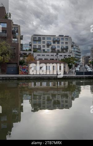 Paris, Frankreich - 11 26 2023: Ourcq Canal. Reflexionen über den Ourcq-Kanal eines alten Steinhauses und eines modernen Gebäudes dahinter Stockfoto