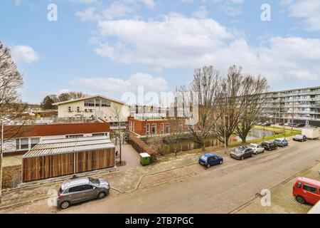 Luftaufnahme von Wohngebäuden mit Autos, die tagsüber auf der Straße in der Stadt geparkt sind, bei bewölktem Himmel Stockfoto