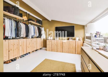Das Innere des modernen Wohnzimmers mit offenem Schrank und Fernseher an der Wand durch ein helles Fenster zu Hause Stockfoto