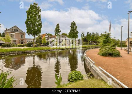 Kanal mit Reflexion von Bäumen in der Nähe von Wohnvillen in der Nachbarschaft der Stadt gegen Himmel Stockfoto