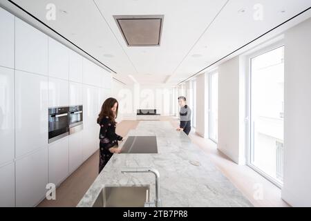 Frau und Mann stehen einander gegenüber auf einer Kücheninsel in einem hellen, modernen Küchenraum Stockfoto
