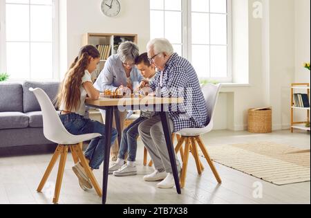 Großeltern bringen ihren Enkeln das Schach bei, während sie zu Hause zusammen sind. Stockfoto