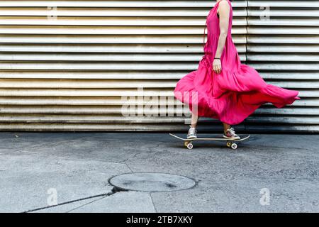 Skater Mädchen in rotem Kleid, das auf einem Skateboard reitet Stockfoto