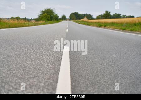 Nahaufnahme von Fahrbahnmarkierungen auf leerem Asphaltweg im ländlichen Schweden im Sommer Stockfoto