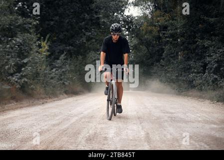 Radfahrer fahren mit dem Schotterrad im Wald. Mann mit Helm und Brille, die in der Natur radelt. Stockfoto