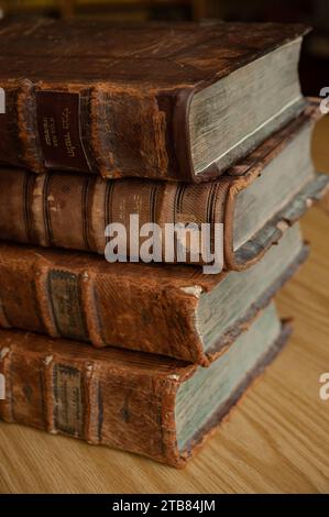 Staubige, abgenutzte und verblasste jüdische Heiligbücher, die in Leder gebunden sind, stehen aufrecht auf einem Bücherregal. Stockfoto