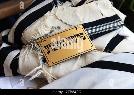 Ein schwarz-goldenes Schild auf Hebräisch, auf dem steht „der wöchentliche Toraabschnitt“, das während der Morgengebete in einer Synagoge auf einem Tallit liegt. Stockfoto