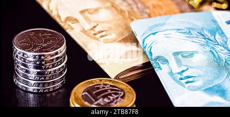 Banknoten von hundert Reais und fünfzig Reais, mit Münzen von einem Real, Geld aus brasilien. Isoliert auf schwarzem Hintergrund. Sparkonzept. Stockfoto