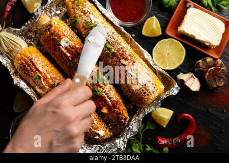 Gegrillter Zuckermais mit geräucherter Paprika-Limette und Butter auf dem Küchentisch, gewürzt mit Tischmesser, Flachansicht Stockfoto