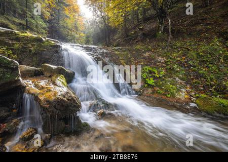 Herbstliche Landschaft mit Wasserfall in einer wunderschönen Hintergrundbeleuchtung. Die felsige Schlucht Dolne Diery im Mala Fatra Nationalpark, Slowakei, Europa. Stockfoto