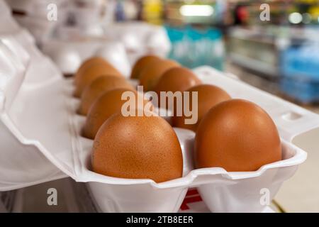 Öffnen Sie die Eierbox mit zehn braunen Eiern. Frische Hühnereier aus biologischem Anbau in der Packung oder im Eierbehälter. Hühnereier im Ladenregal. Stockfoto