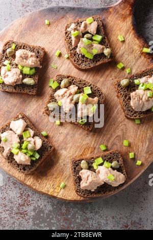 Frische Meeresfrüchte gesundes Essen Sandwich mit Kabeljauleber auf Roggenbrot Sandwiches mit Kabeljauleber in Dosen, grüne Zwiebeln und Kapern Nahaufnahme auf einem Holzbrett o Stockfoto
