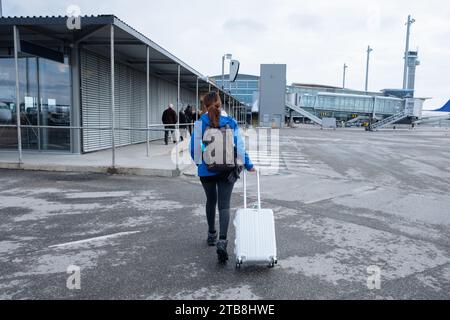 Junge weibliche Touristen, die mit Gepäck unterwegs waren, kamen auf der Landebahn zum Flughafen an Stockfoto