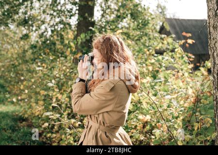 Rothaariges Mädchen in beigem Trenchcoat im Herbst Stockfoto