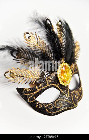 Schwarze Karnevalsmaske mit goldenen Elementen, gelbem Edelstein und schwarzen Federn. Stockfoto