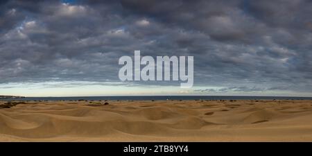 Natürliche Sanddünen von Maspalomas in der Nähe von Maspalomas, Spanien (Panoramablick) mit Wolken über den Dünen bei Sonnenuntergang. Stockfoto