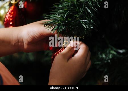 Der Junge, der den weihnachtsbaum in seinem Haus vor der Weihnachtsfeier zusammenstellt. Nahaufnahme der Hände. Stockfoto